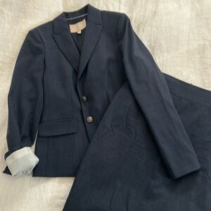 Woman’s two-piece skirt suit. Skirt hits just at knee. Fitted and classic.